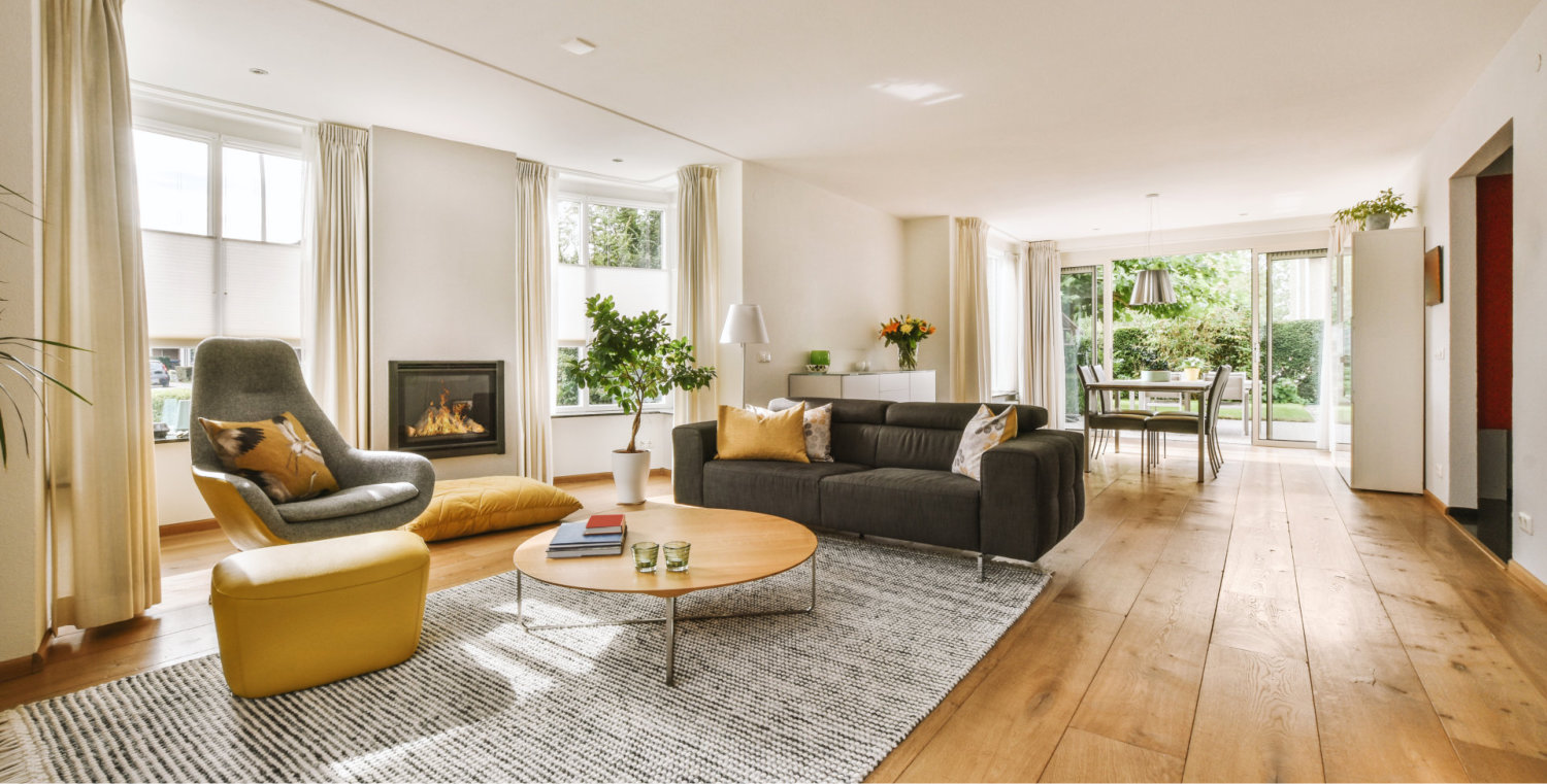 Contemporary minimalist style interior design of light studio apartment with wooden table and chairs in dining zone between open kitchen and living room with white walls and parquet floor